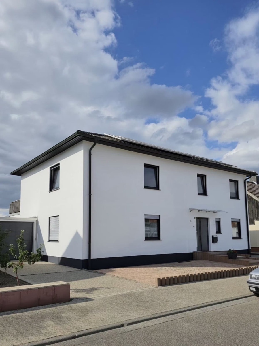 Dasselbe Haus nach der Renovierung: weiße Fassade mit anthrazitfarbenem Sockel