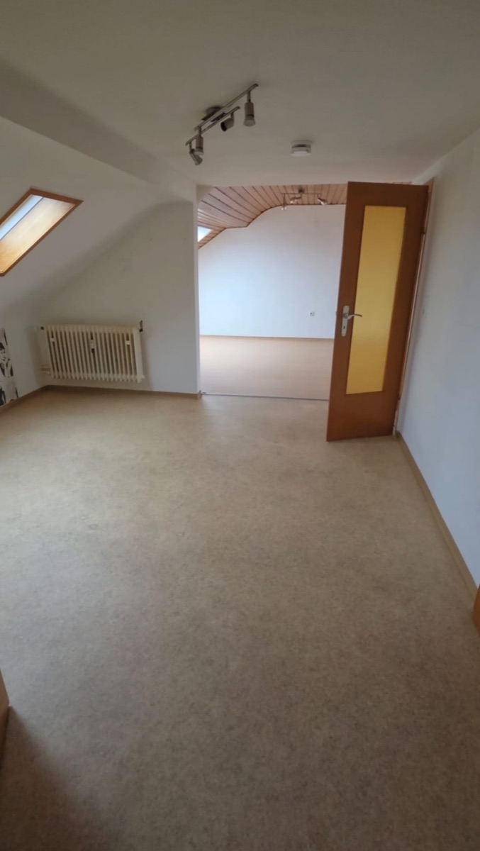 Dachgeschosswohnung vor der Renovierung: tapezierte Wände, Holztür, alter heller Bodenbelag